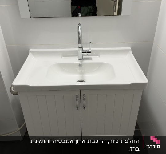 כיור רחצה לבן וברז כרום מותקנים על ארון אמבטיה